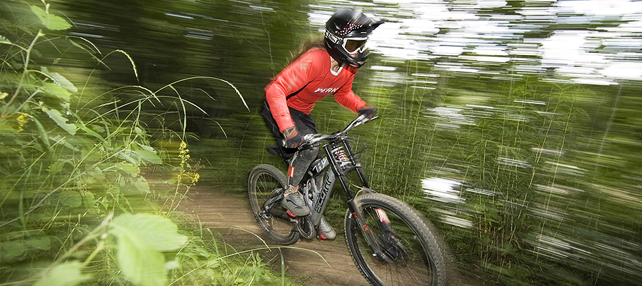 Mountainbike i full fart utför skogsbacke